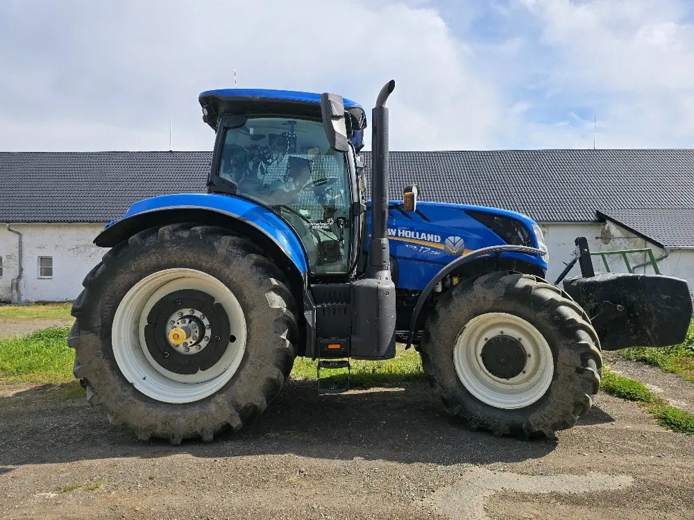 Traktor New Holland před stájí farmy